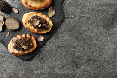 Delicious bruschettas with truffle sauce on grey table, flat lay. Space for text