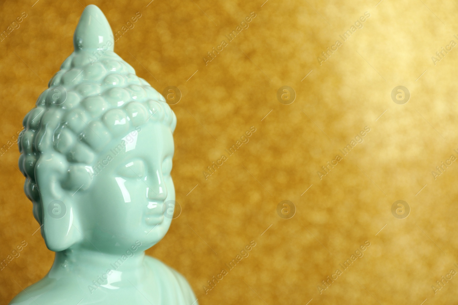 Photo of Buddha statue on golden background, closeup. Space for text