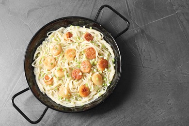 Photo of Delicious scallop pasta with green onion on grey table, top view. Space for text