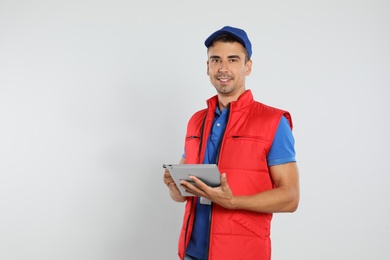 Photo of Happy young courier with tablet on white background