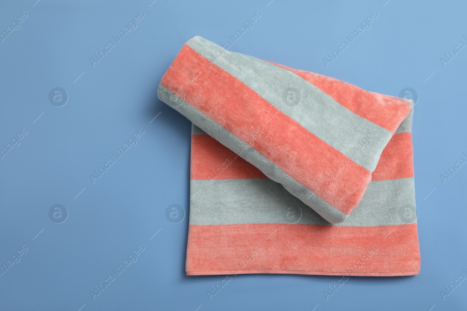 Photo of Striped beach towel on blue background, top view
