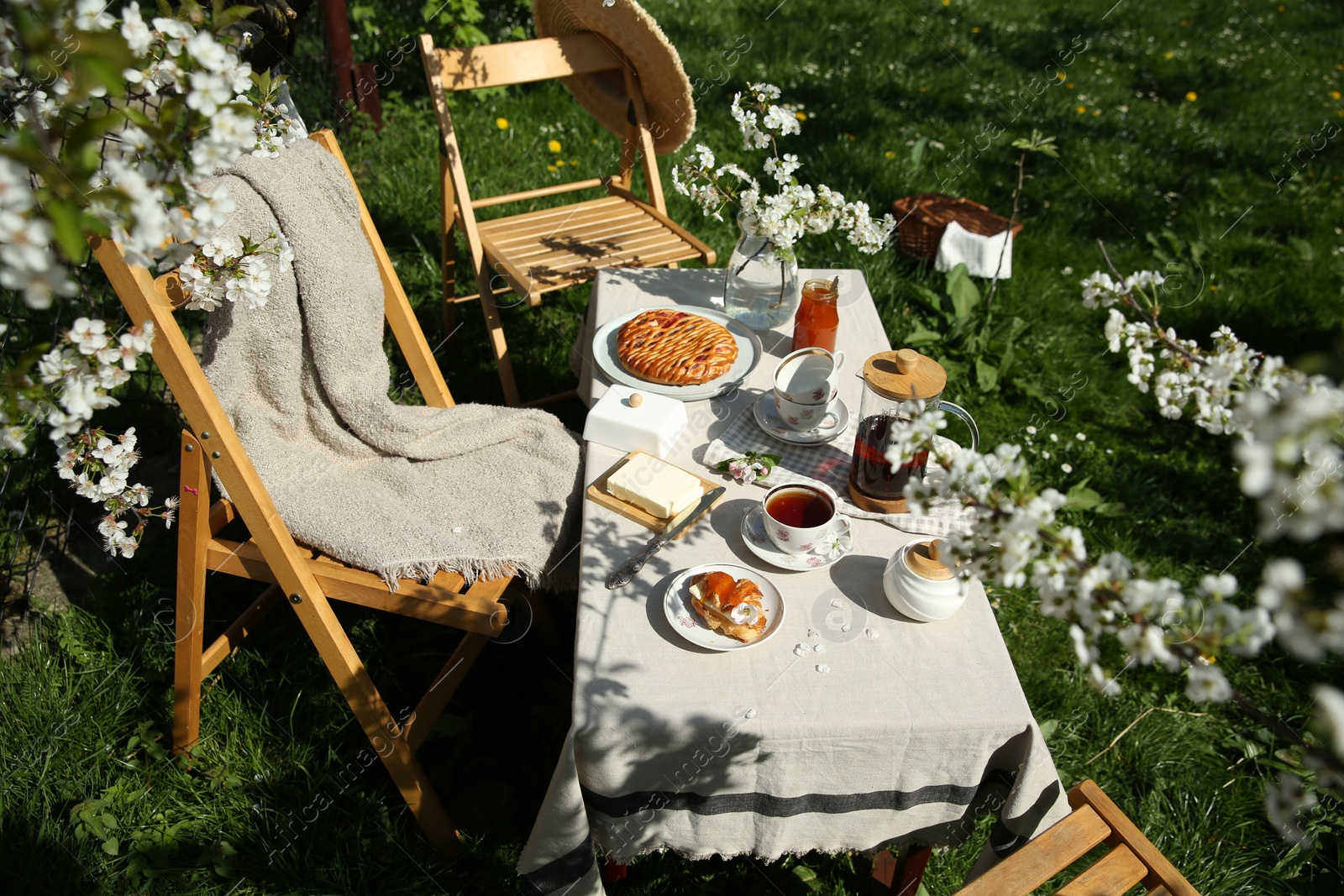 Photo of Beautiful table setting with spring flowers in garden on sunny day