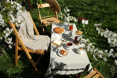 Photo of Beautiful table setting with spring flowers in garden on sunny day