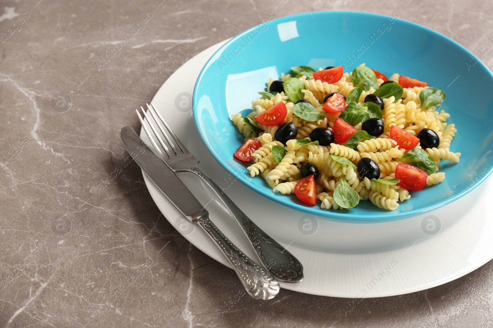 Photo of Plate with delicious pasta primavera on grey background