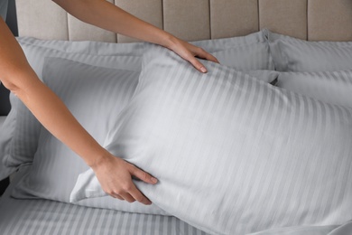 Photo of Woman putting soft pillow on bed, closeup