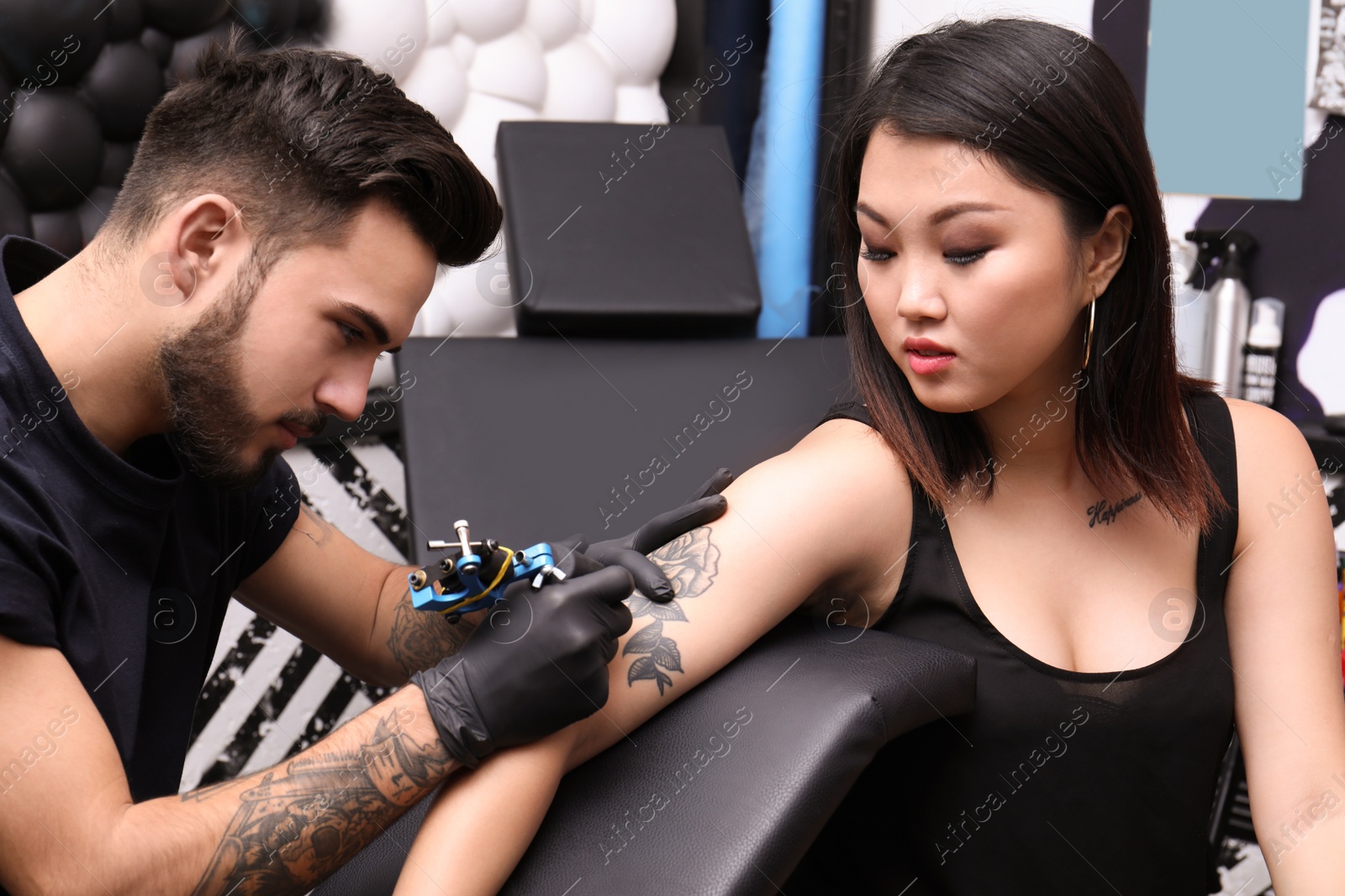 Photo of Professional artist making tattoo with machine in salon