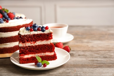 Photo of Plate with piece of delicious homemade red velvet cake on table. Space for text