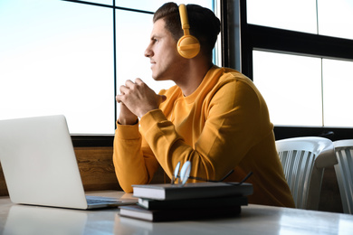 Man listening to audiobook at table in cafe