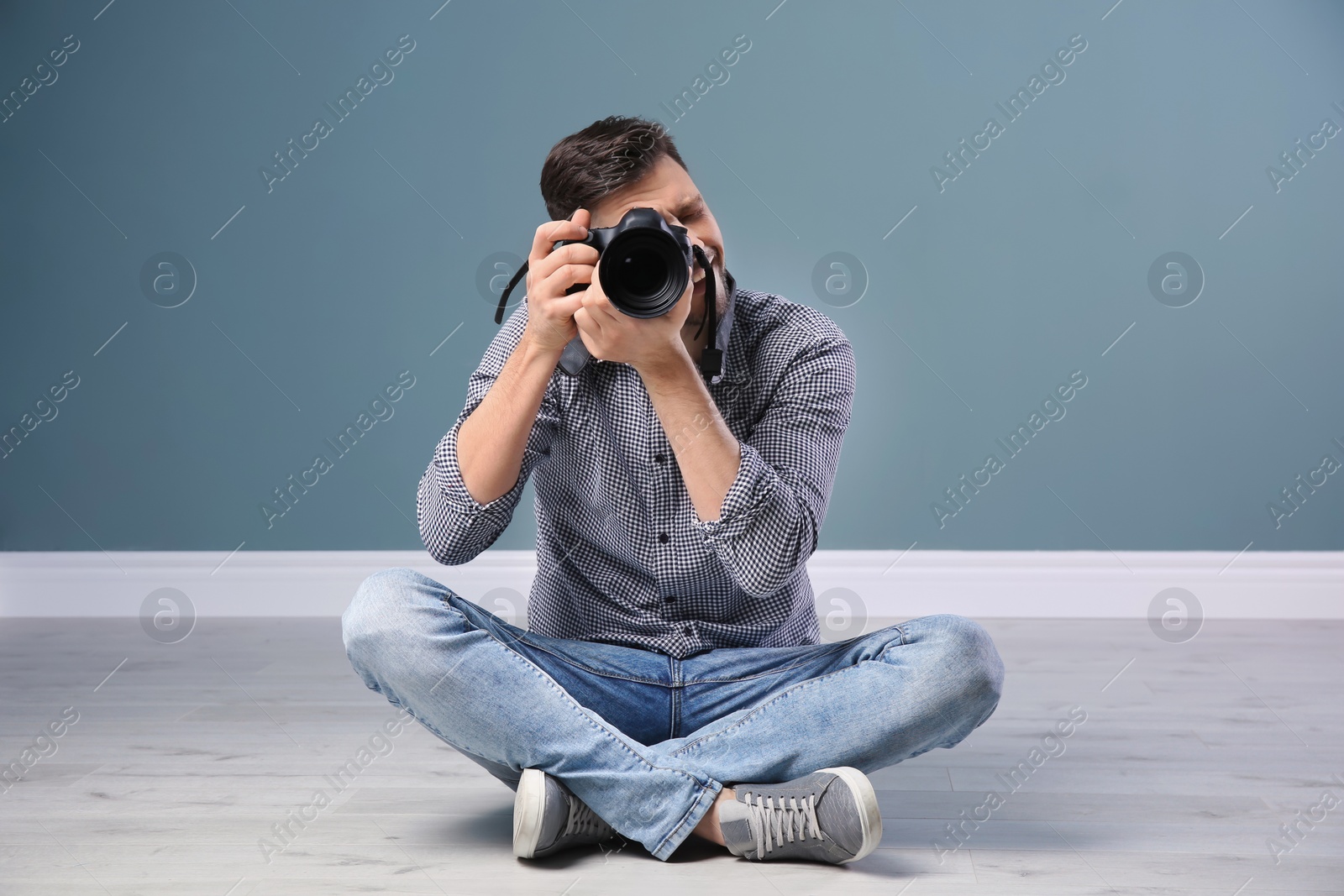 Photo of Male photographer with camera near grey wall