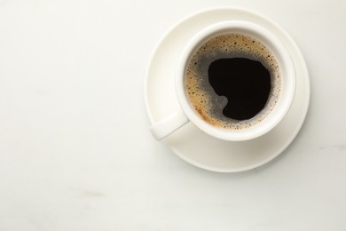 Photo of Cup of aromatic coffee on white table, top view. Space for text