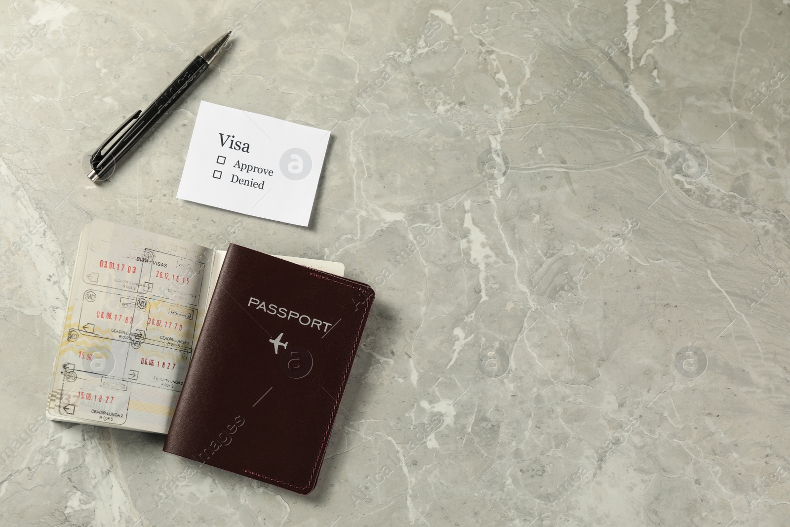 Photo of Moldova, Ceadir-Lunga - June 13, 2022: Flat lay composition with passports, pen and visa permission on grey marble table. Space for text