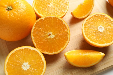 Photo of Ripe oranges on wooden board, closeup view