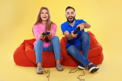 Photo of Emotional couple playing video games with controllers on color background