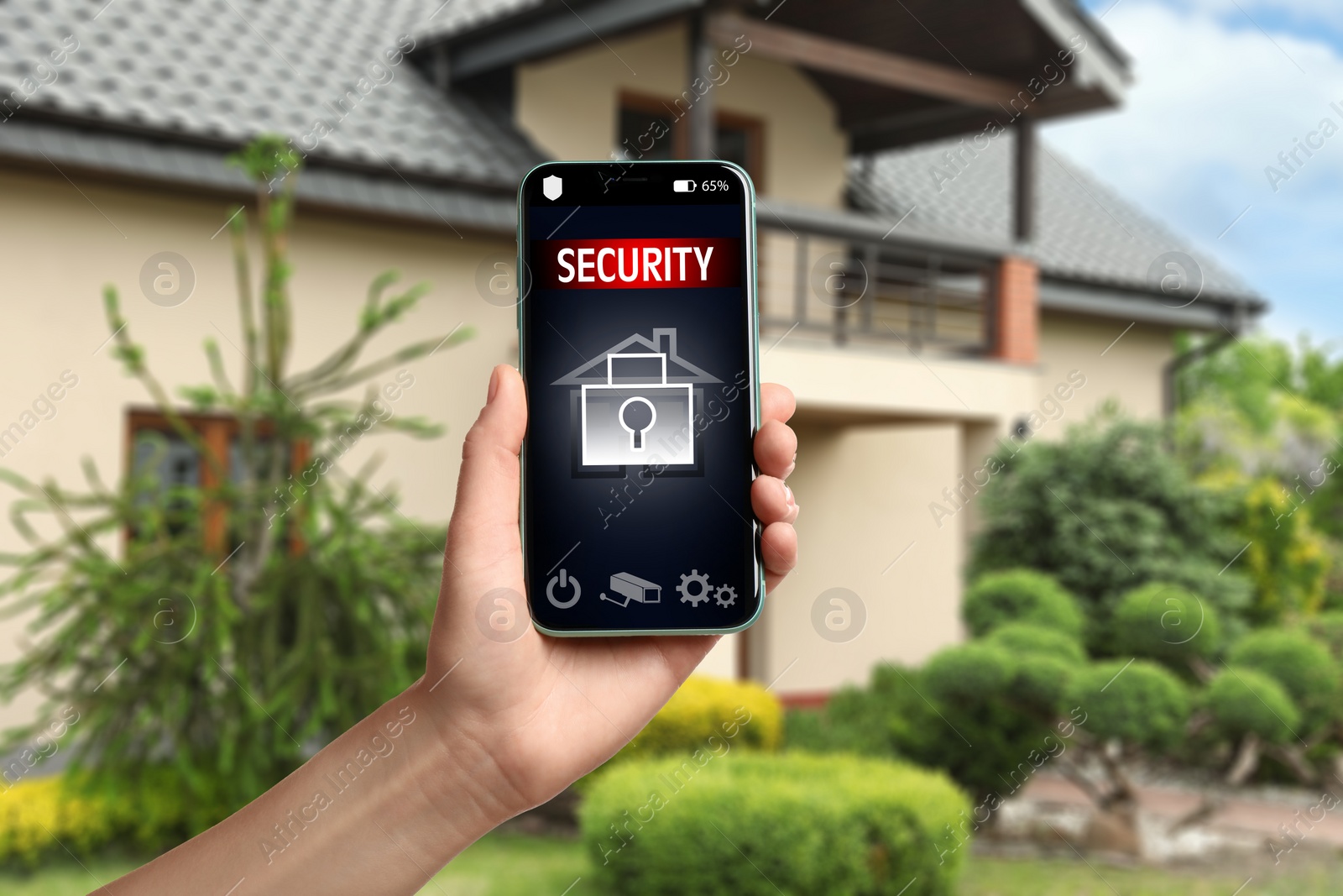 Image of Woman using home security system application on smartphone outdoors, closeup