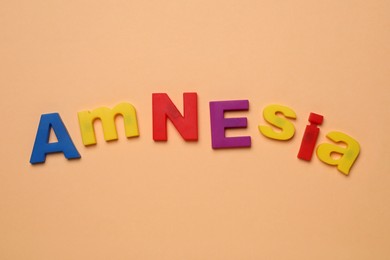 Photo of Word Amnesia made of colorful letters on orange background, flat lay