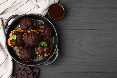 Delicious profiteroles with chocolate and mint on grey wooden table, flat lay. Space for text