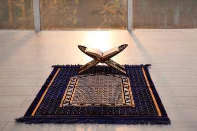 Photo of Rehal with open Quran on Muslim prayer rug indoors