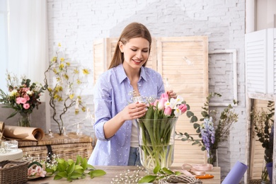 Photo of Female decorator creating beautiful bouquet at table