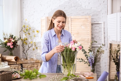 Female decorator creating beautiful bouquet at table