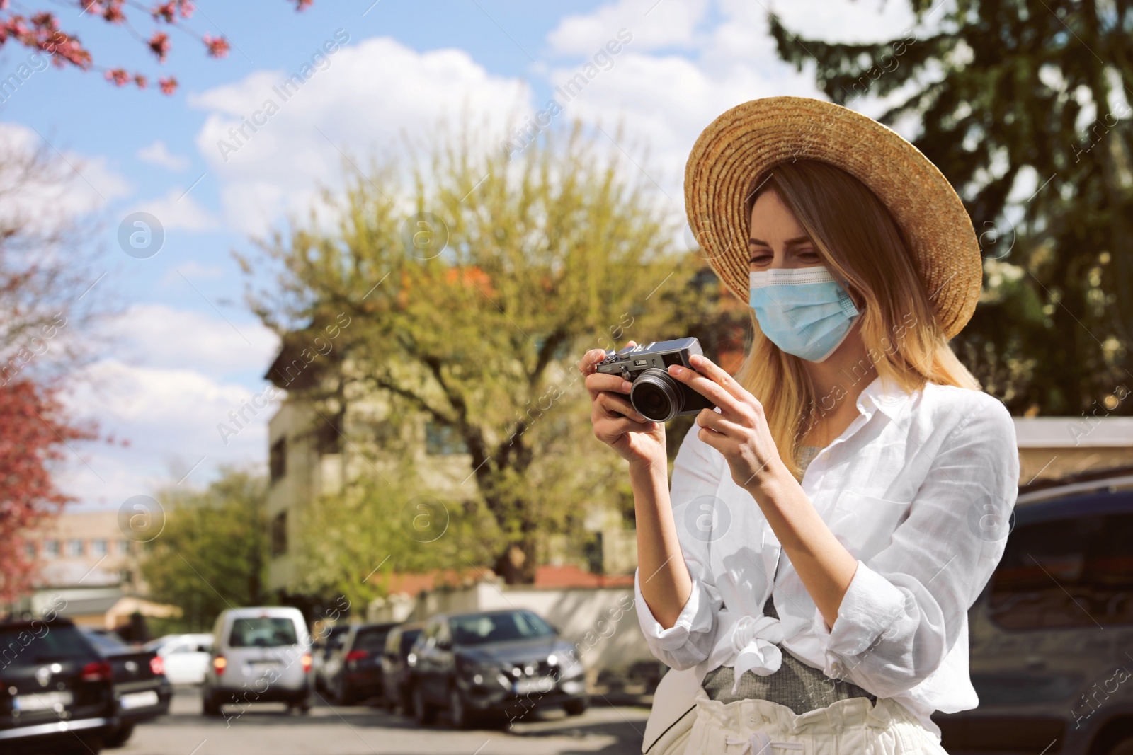 Photo of Female tourist with protective mask and camera on city street