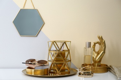 Photo of Composition with golden accessories on dressing table near color wall. Space for text