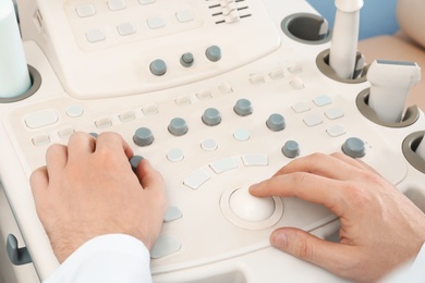 Photo of Sonographer operating modern ultrasound machine in clinic, closeup