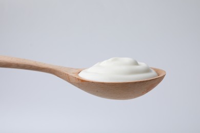 Delicious natural yogurt in spoon on light background