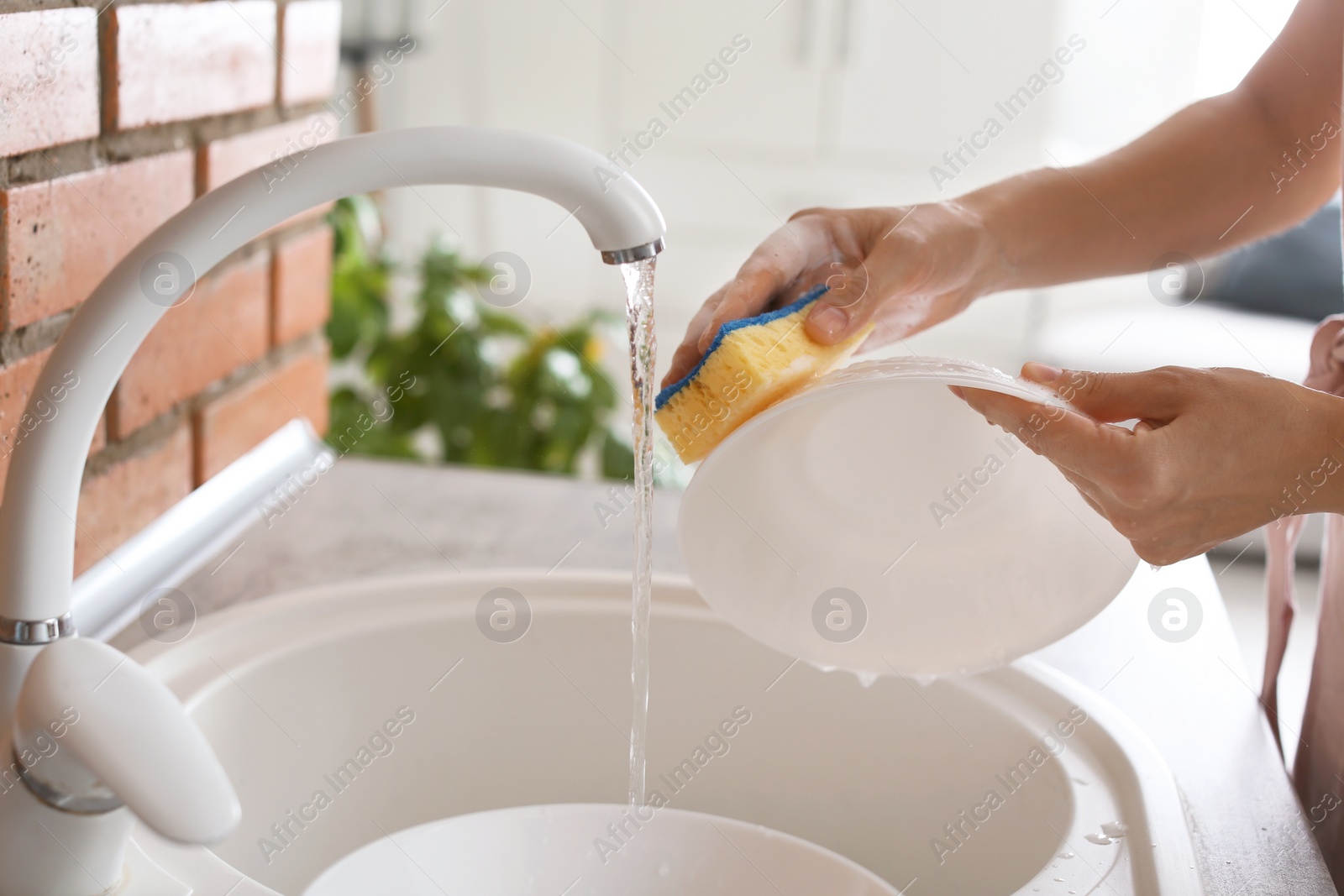 Photo of Woman washing dishes in kitchen sink, closeup view. Cleaning chores