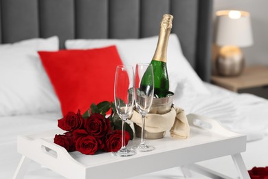 Honeymoon. Sparkling wine, glasses and bouquet of roses on table in room