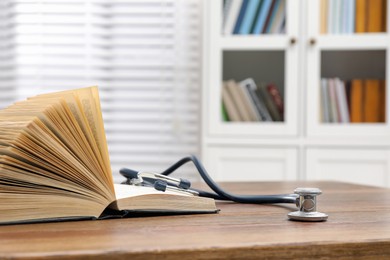 Photo of Book and stethoscope on wooden table indoors, space for text. Medical education