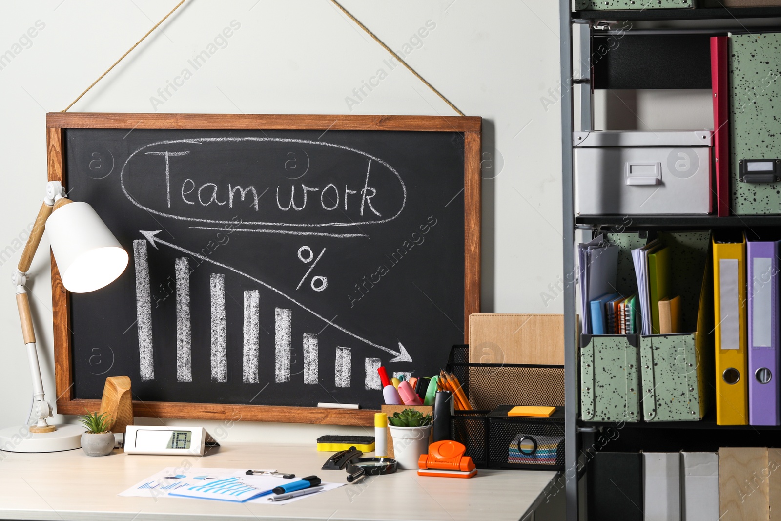 Photo of Business process planning and optimization. Workplace with lamp, blackboard, graphs and other stationery on wooden table