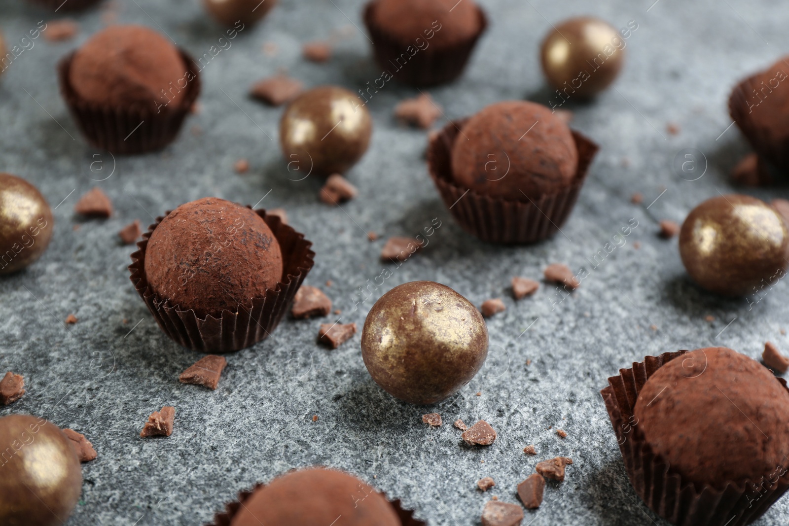 Photo of Different delicious chocolate candies on grey table, closeup
