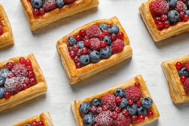 Fresh delicious puff pastry with sweet berries on light table, above view