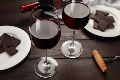 Photo of Tasty red wine and chocolate on wooden table
