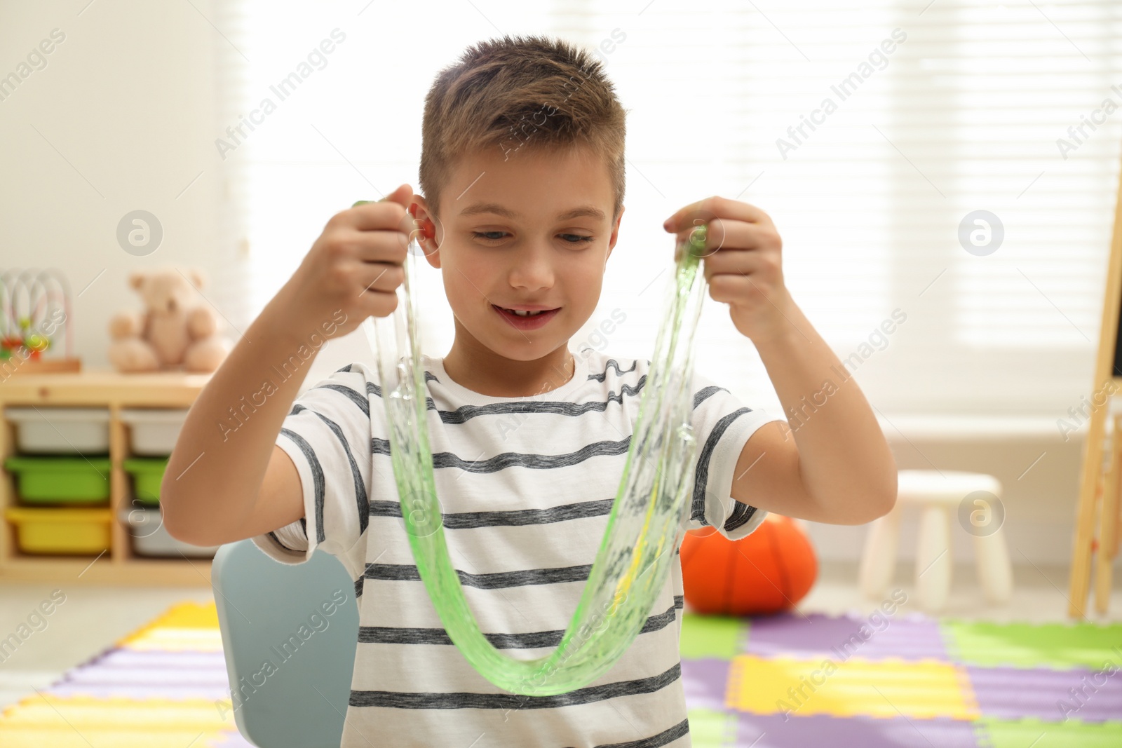 Photo of Little boy playing with slime in room