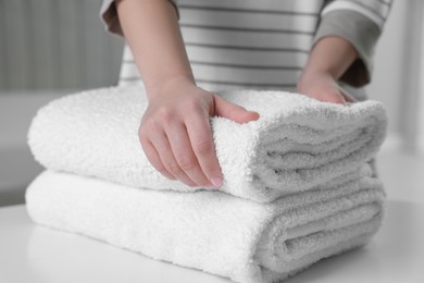 Photo of Woman touching soft white towel indoors, closeup