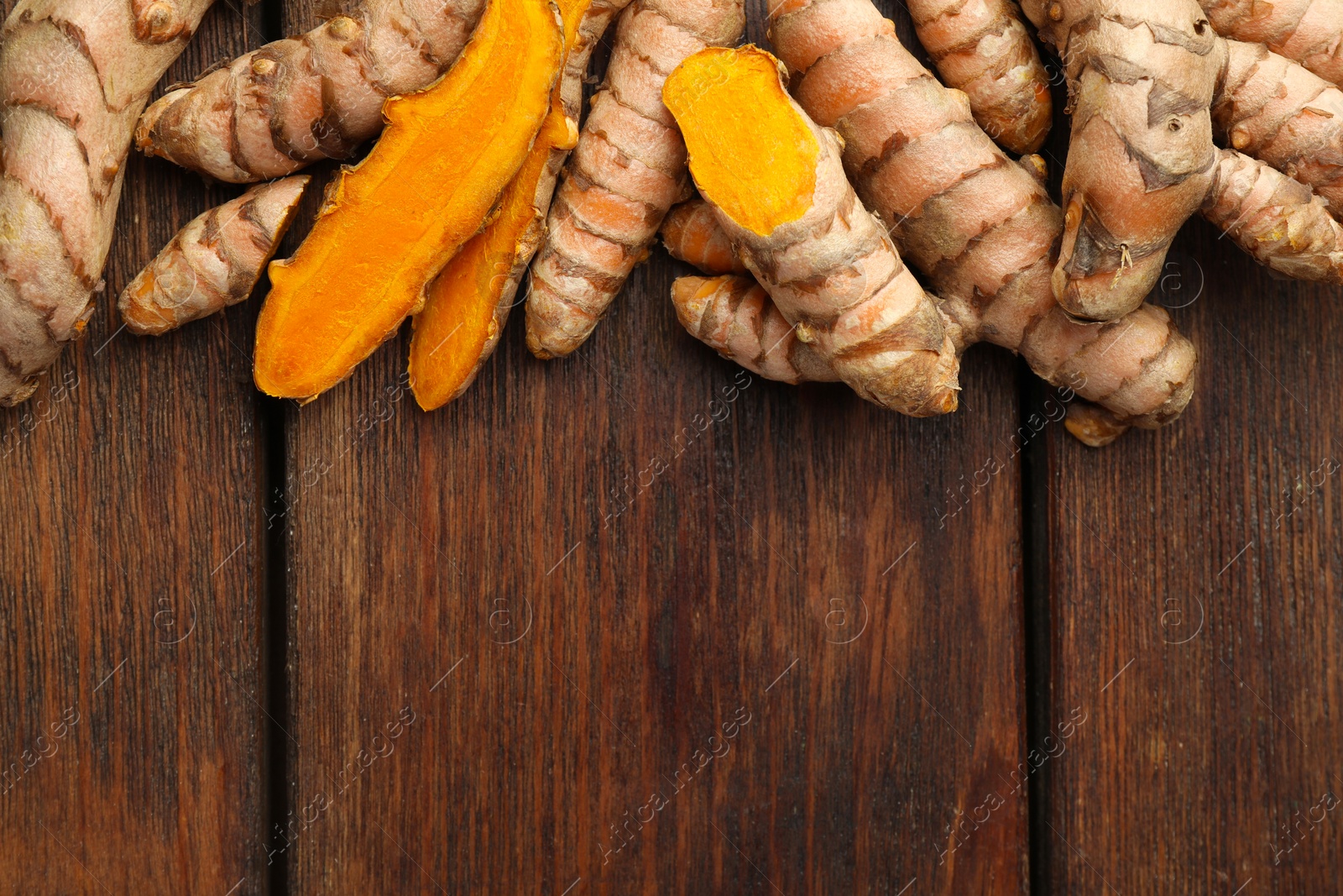 Photo of Many fresh turmeric roots on wooden table, flat lay. Space for text