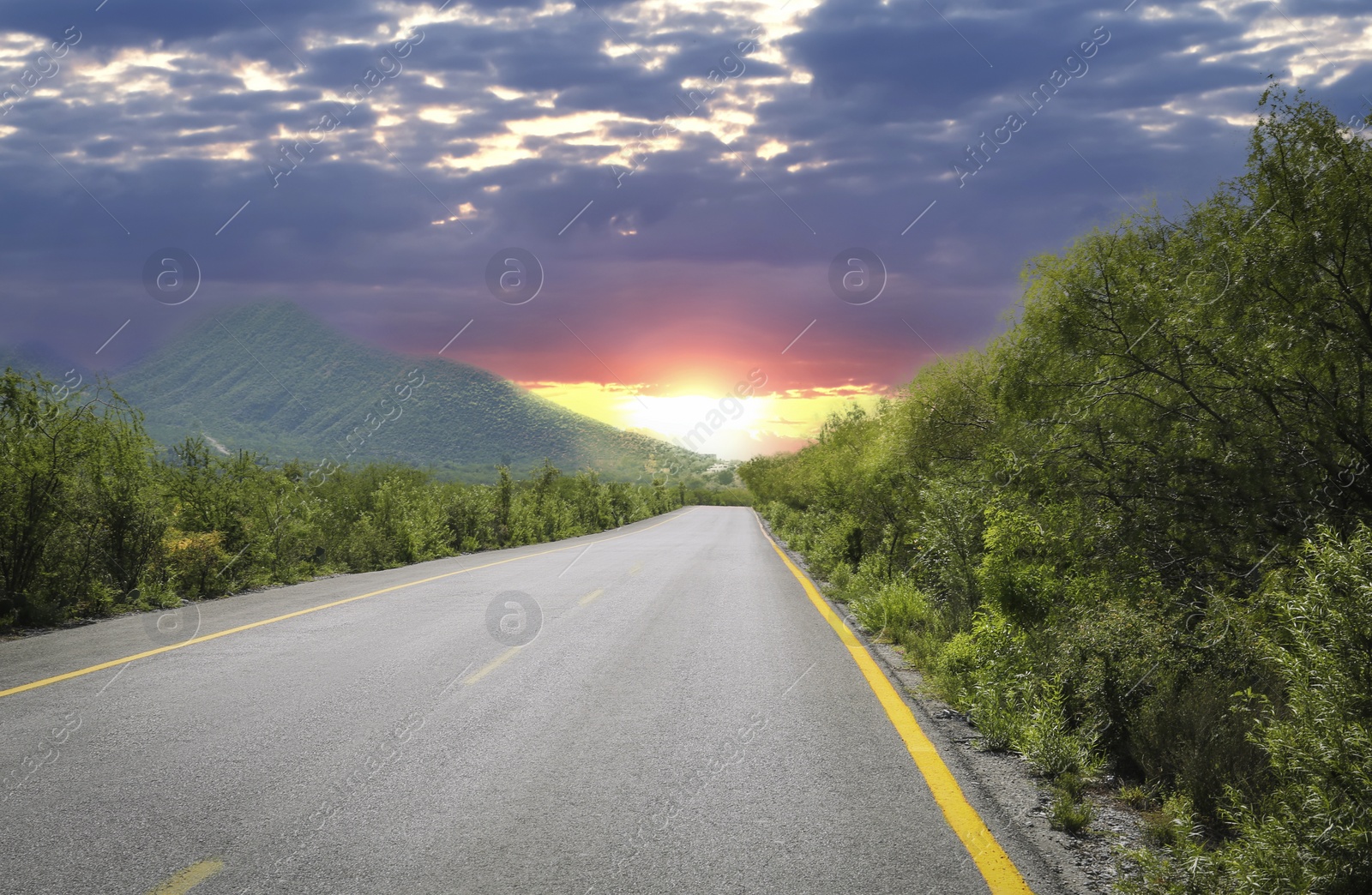 Image of Empty asphalt road, trees and mountain at beautiful sunset