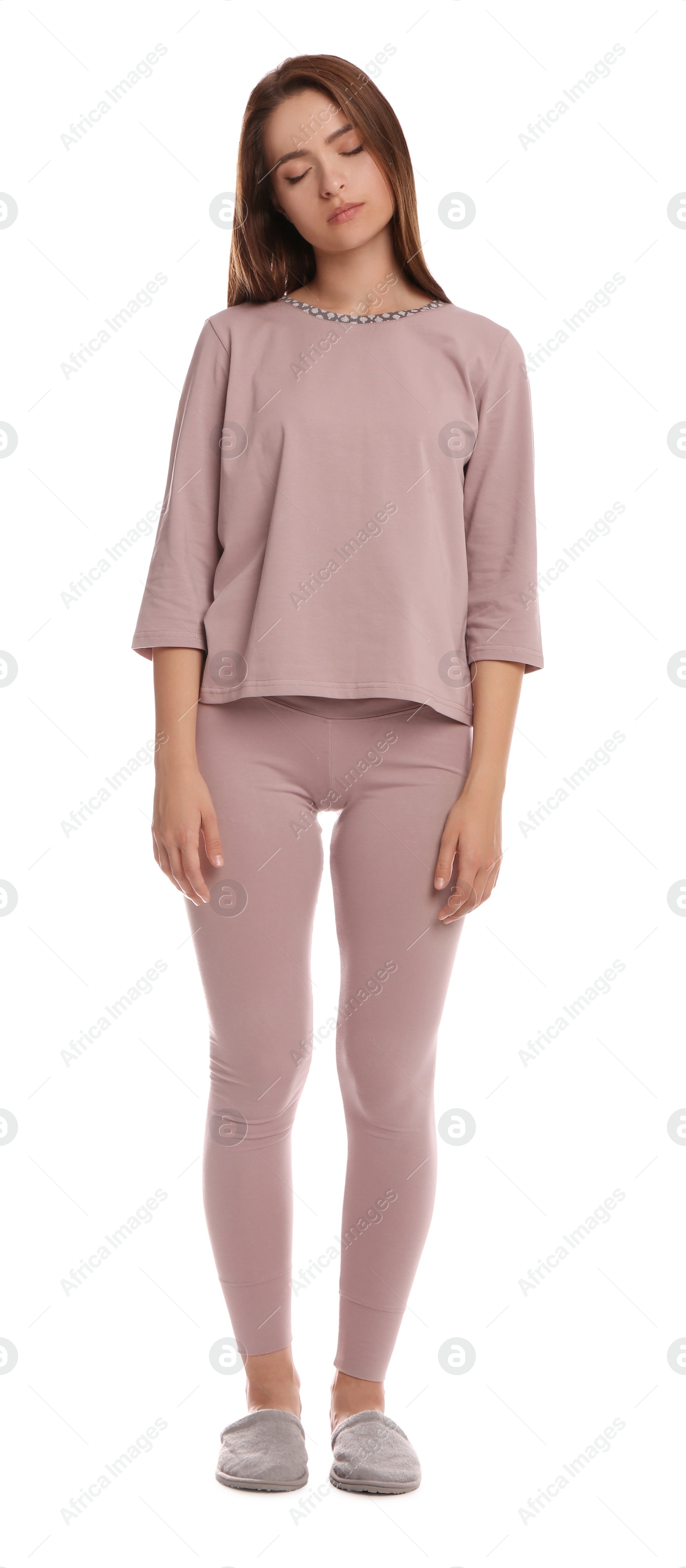 Photo of Young woman wearing pajamas and slippers in sleepwalking state on white background