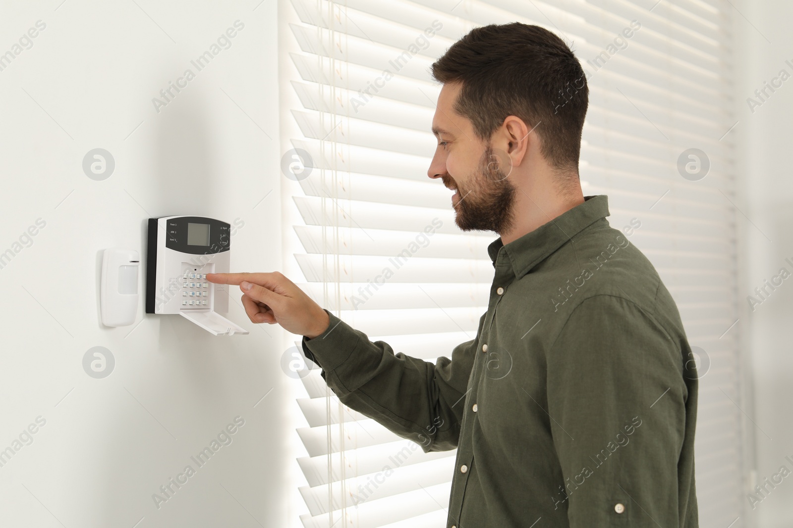 Photo of Man entering code on home security system indoors