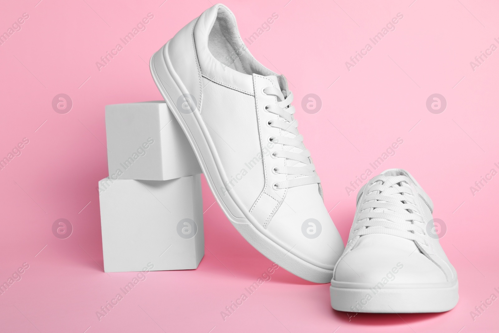 Photo of Pair of stylish white sneakers on pink background