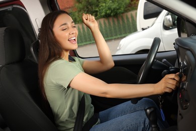 Photo of Choosing favorite radio. Beautiful woman pressing button on vehicle audio in car