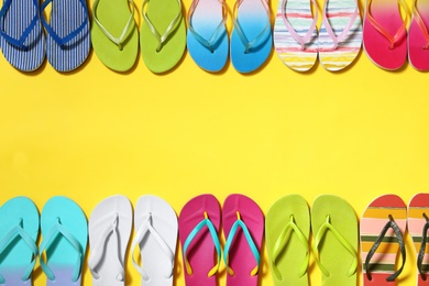 Photo of Different flip flops and space for text on yellow background, flat lay. Summer beach accessories