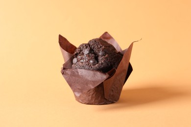 Tasty chocolate muffin on pale orange background