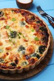 Photo of Delicious homemade quiche with salmon and broccoli on light blue wooden table