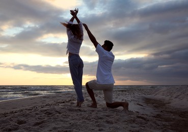 Photo of Happy couple dancing on beach at sunset