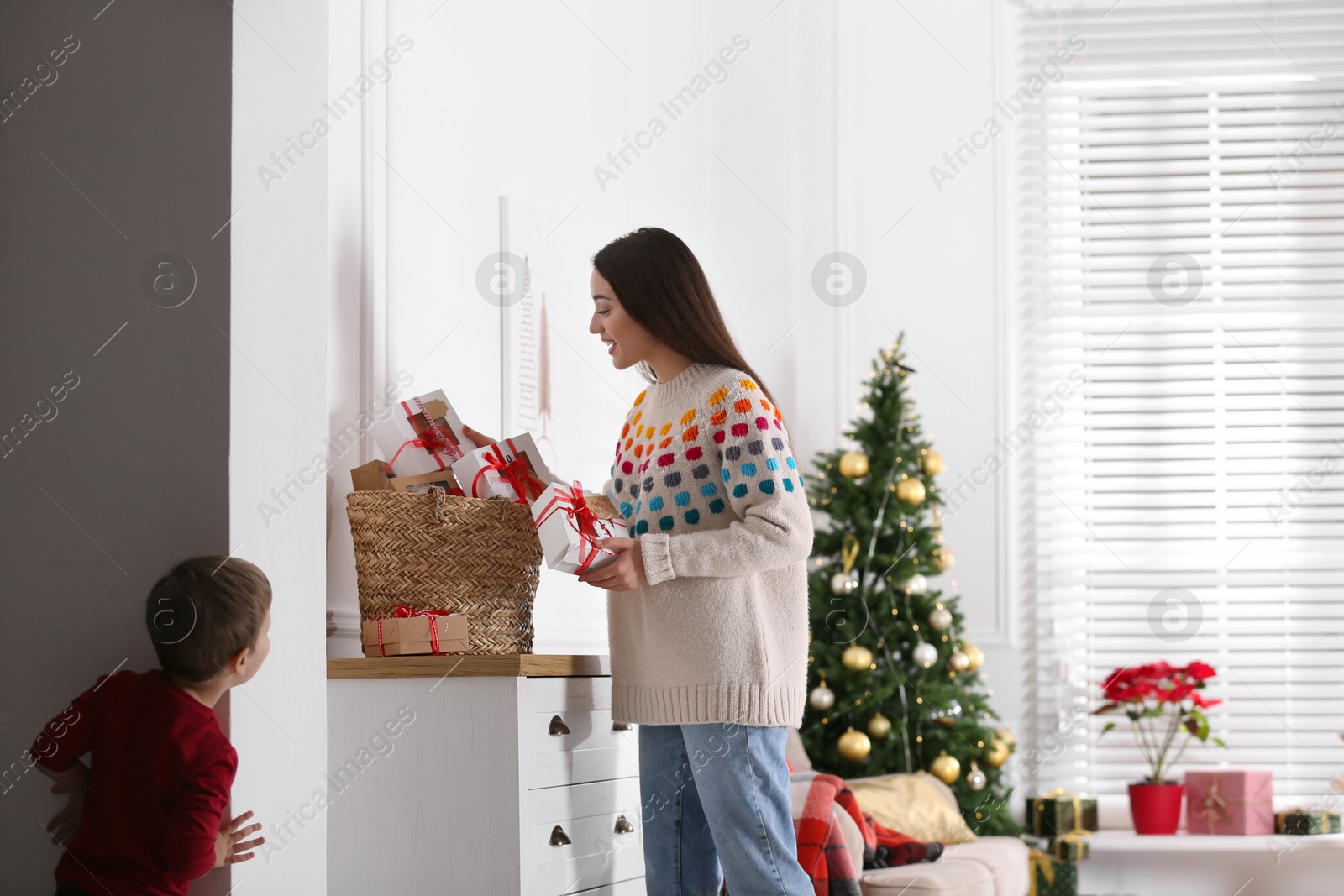 Photo of Little boy watching his mother taking gift from Advent calendar at home. Christmas tradition