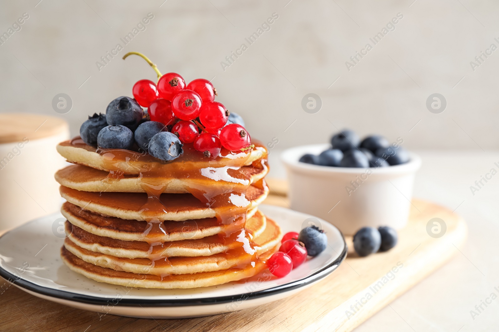 Photo of Delicious pancakes with fresh berries and syrup on table