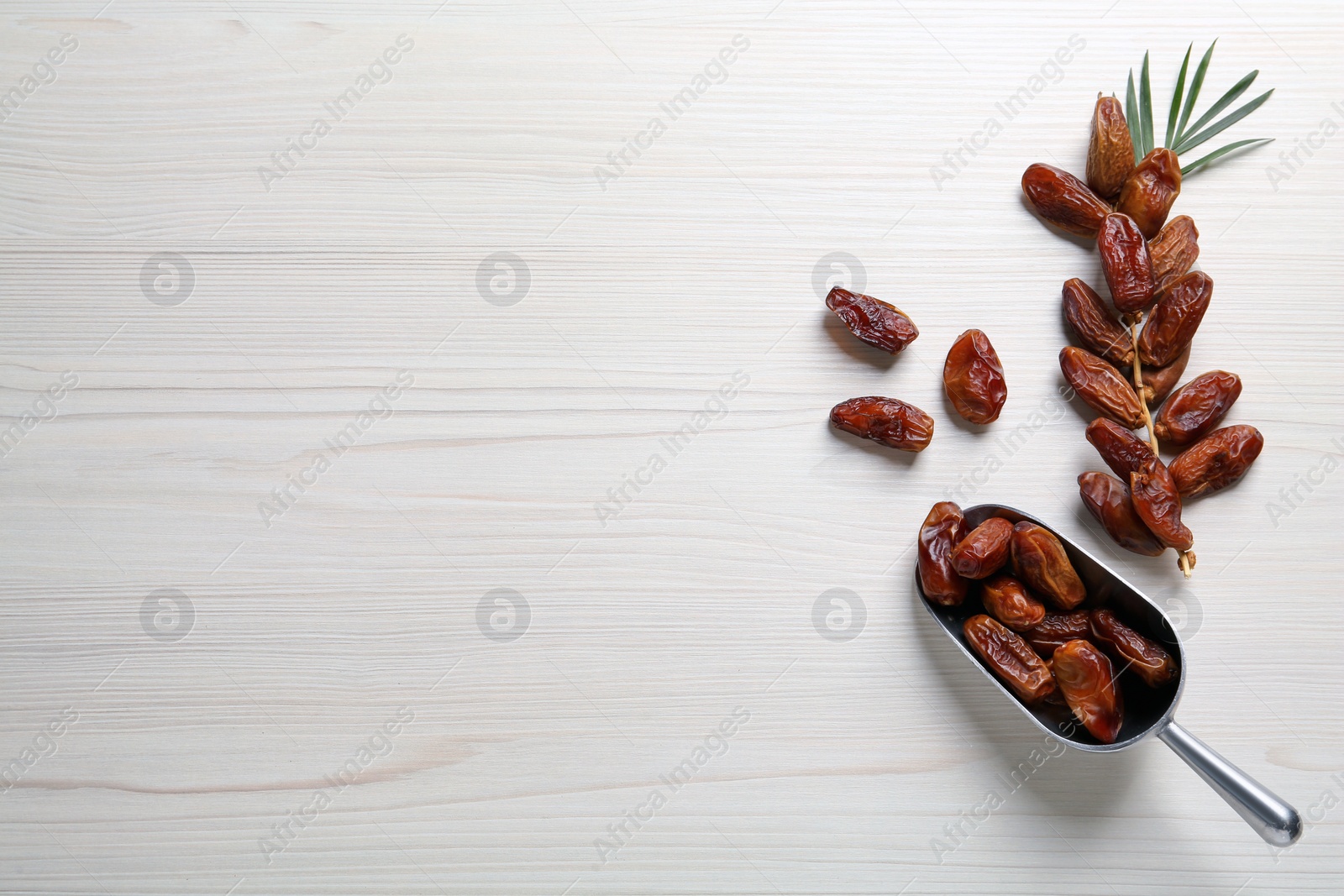 Photo of Sweet dried dates and green leaf on white wooden table, flat lay. Space for text