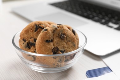 Bowl with chocolate chip cookies on white wooden table in office, closeup